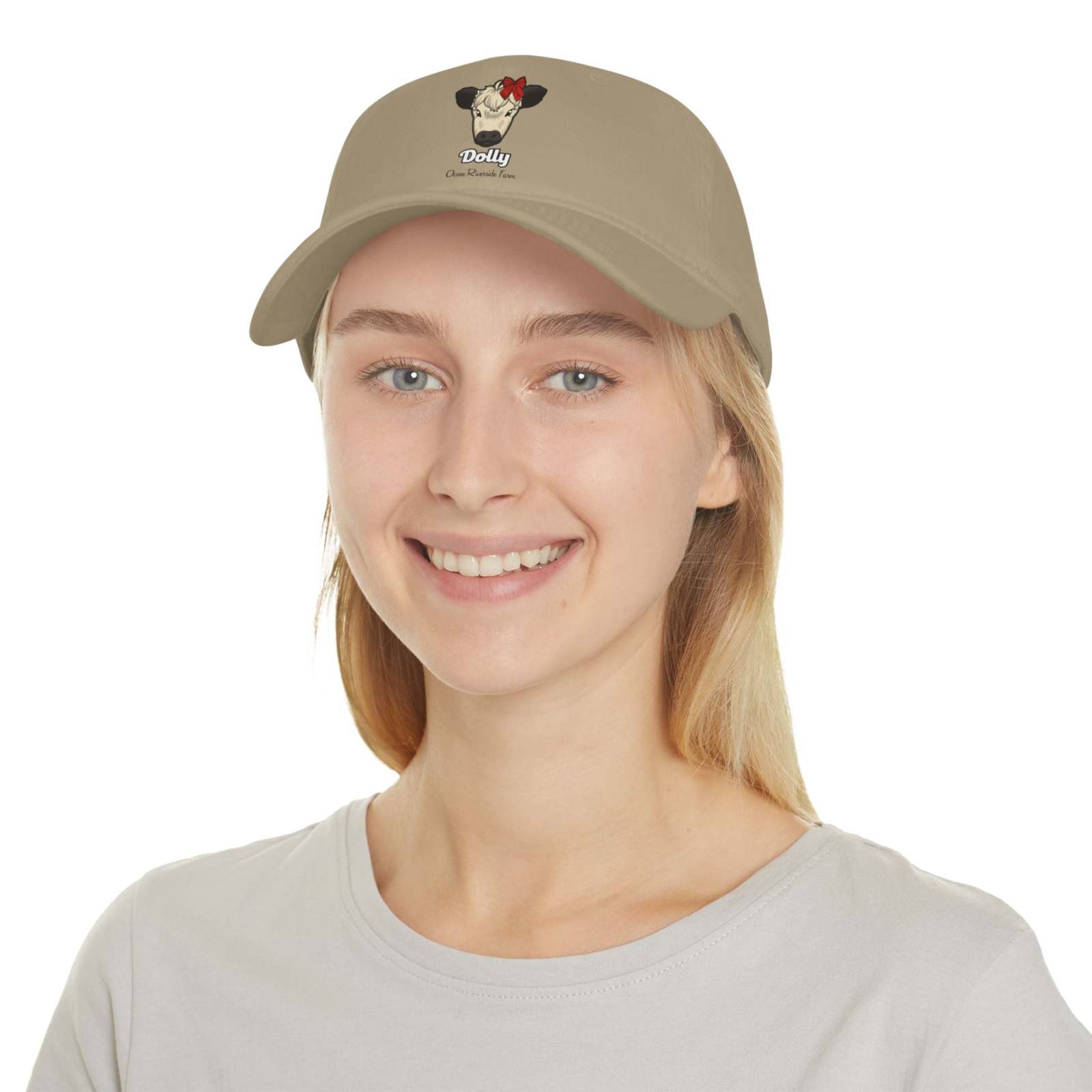Beige cow baseball cap with red bow embroidery worn by smiling woman