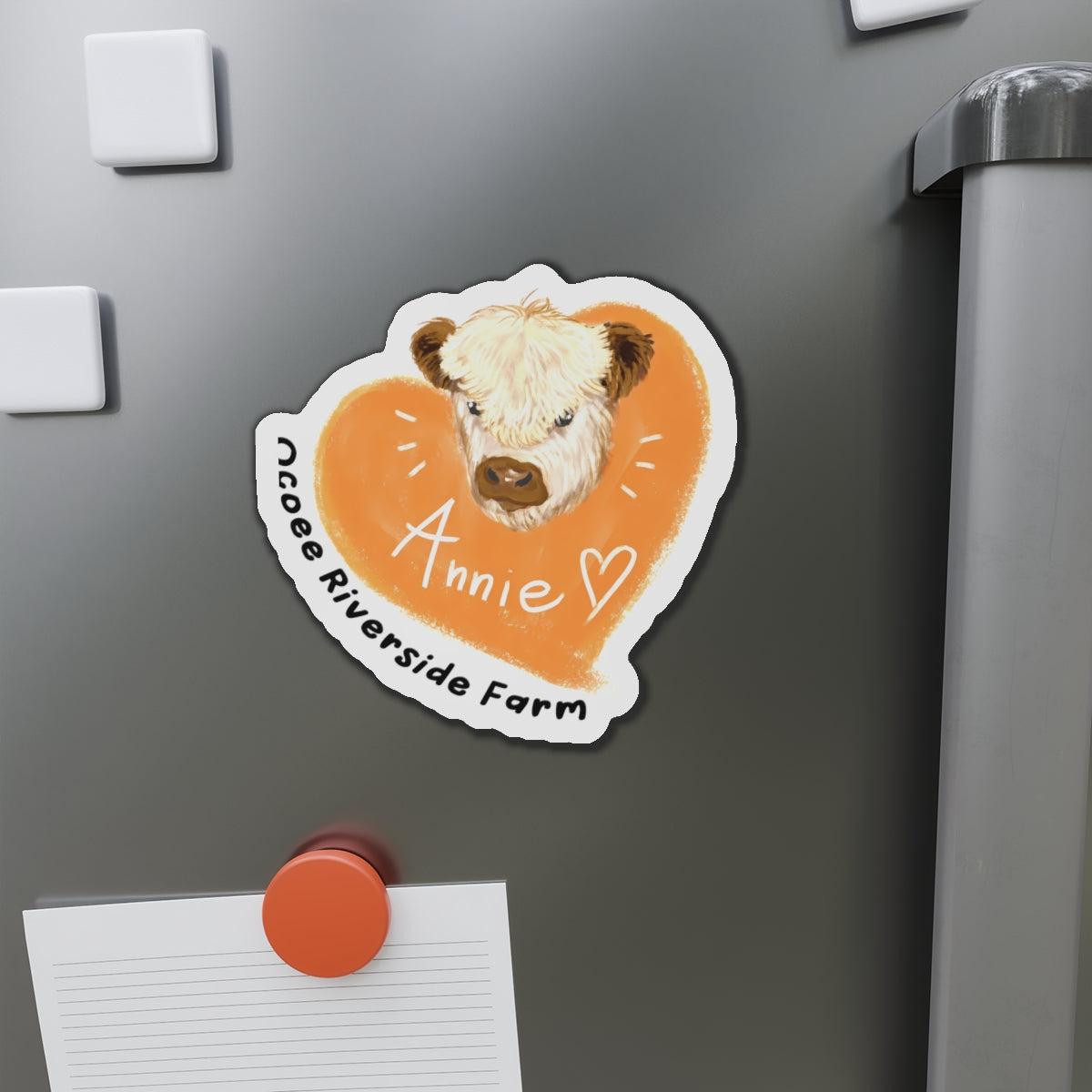 Cute cow design die-cut magnet with farm animal illustration and personalized name on orange background on a refrigerator door