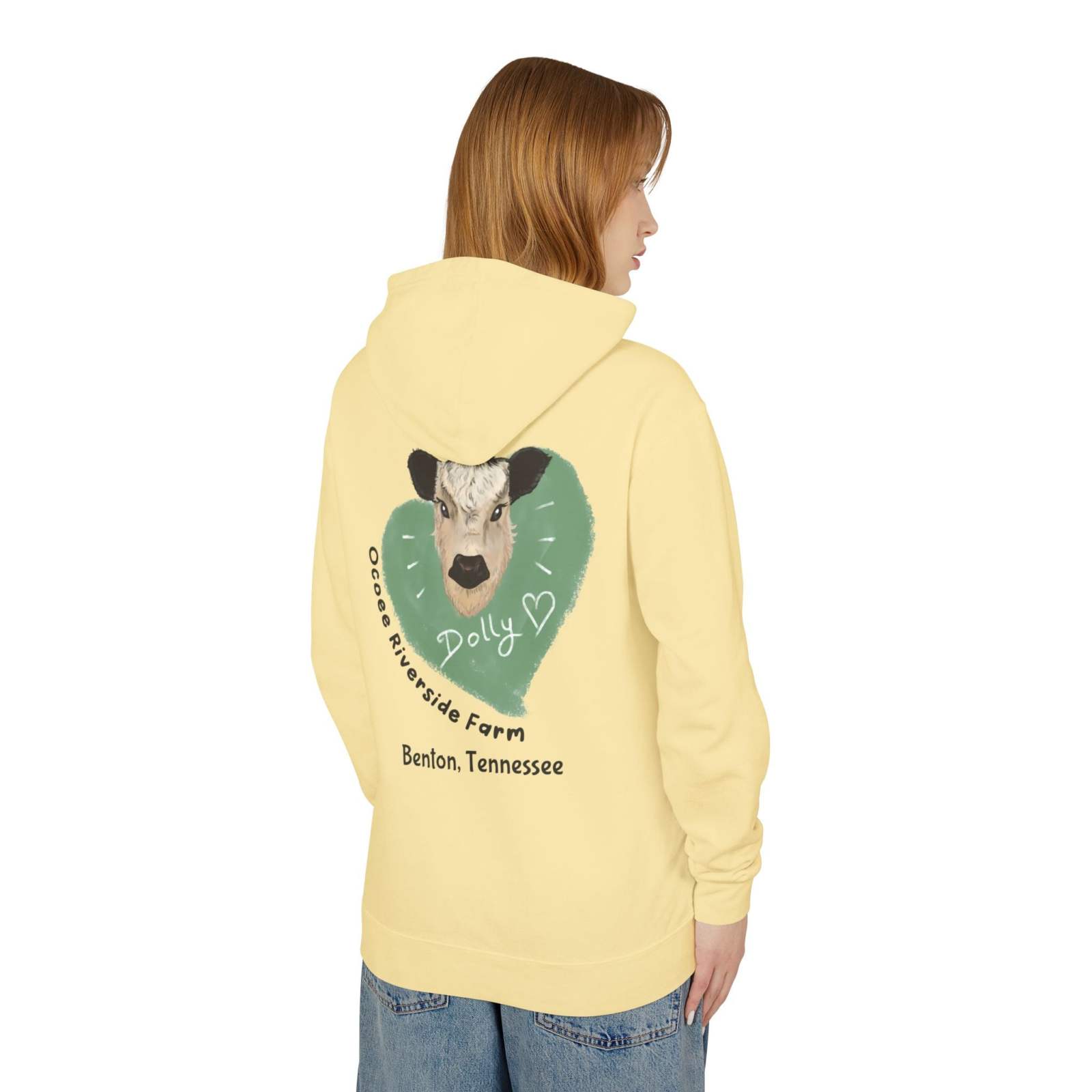 Woman wearing a yellow Cozy Cow Hoodie with a cow and heart graphic on the back, representing Ocoee Riverside Farm, Benton Tennessee.