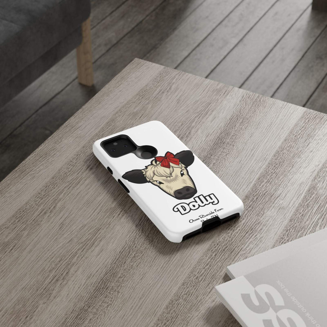 Farmhouse Chic Phone Case with Dolly the Red Bow Cow design on a wooden table.