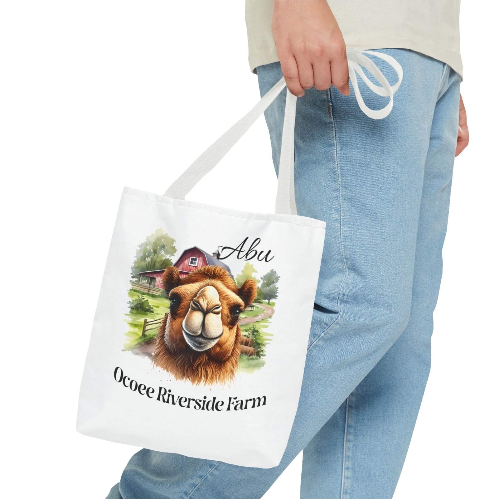 Person holding eco-friendly Abu Camel Tote Bag with camel illustration and Ocoee Riverside Farm text