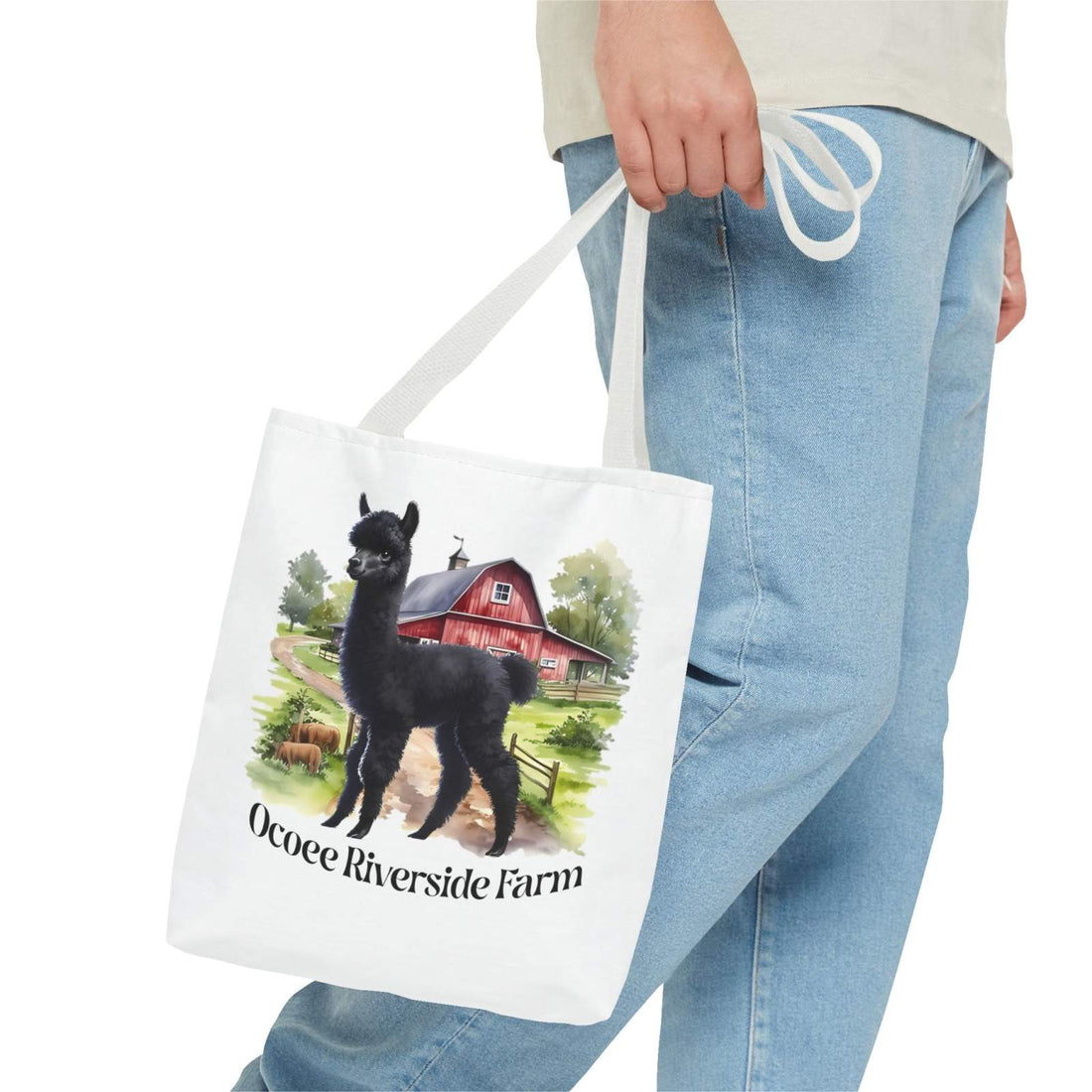 Person holding white eco-friendly llama tote bag with Ocoee Riverside Farm design and red barn illustration
