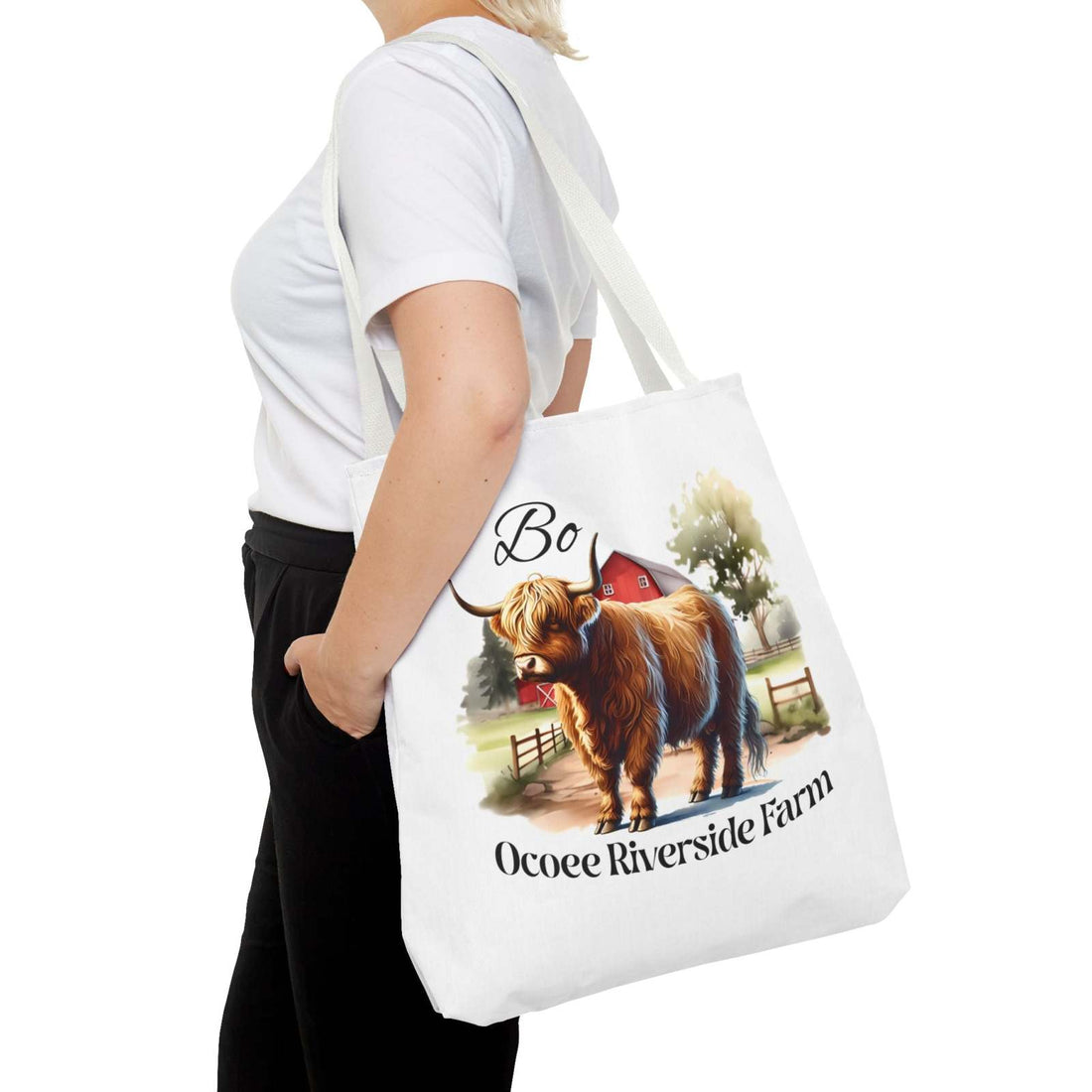 Woman carrying Bo Scottish Highland tote bag with farm animal design and Ocoee Riverside Farm text