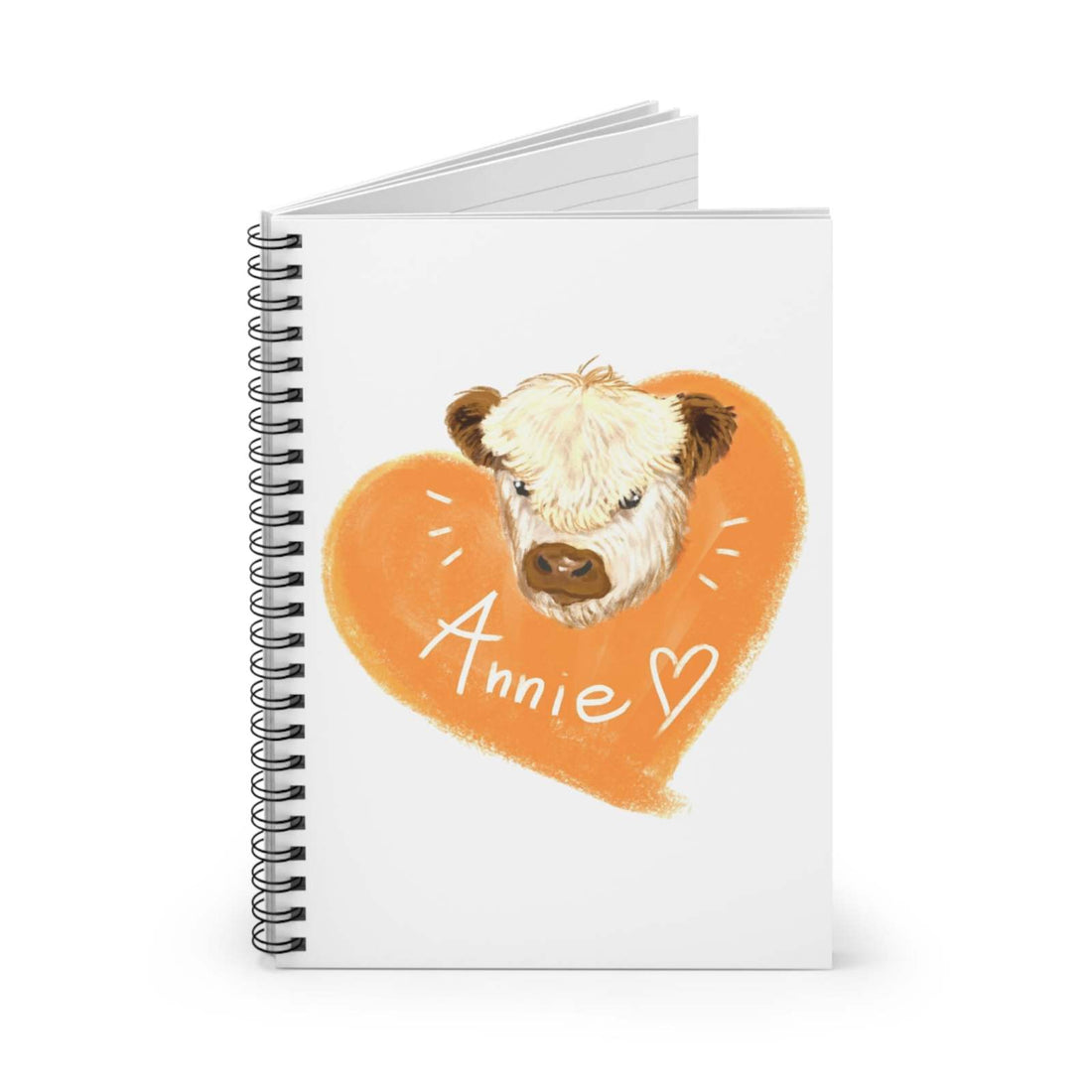 Cute Cow Spiral Notebook featuring "Annie" cow illustration on white cover with orange heart background, spiral-bound with ruled pages.