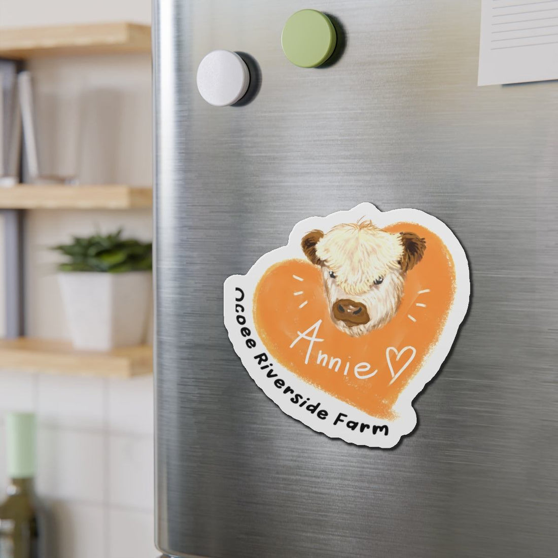 Cute cow design die-cut magnet with orange heart and "Annie" text on a refrigerator door.