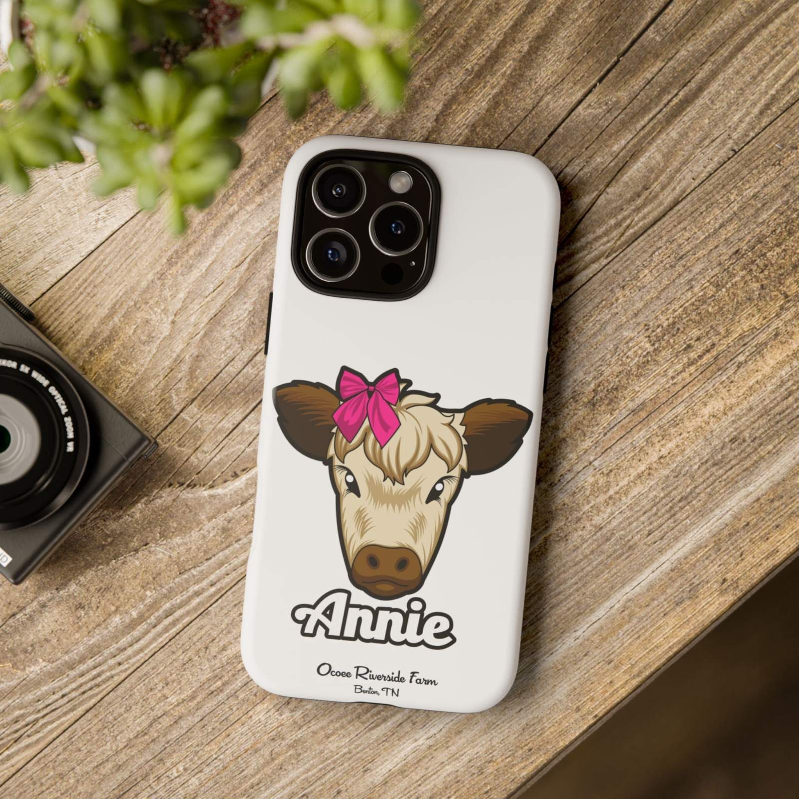Annie the Cow phone case with red bow on wooden table, farm animal lover gift.