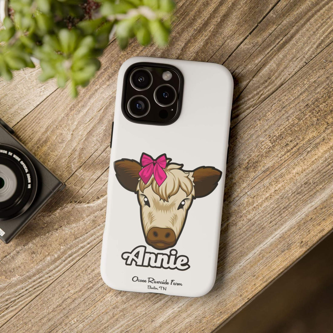 Annie the Cow phone case with red bow on wooden table, farm animal lover gift.