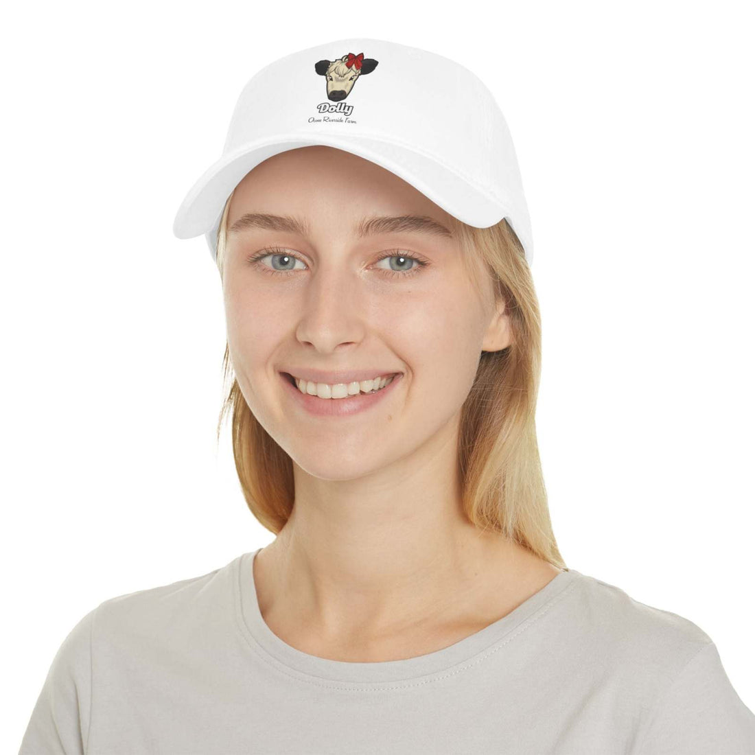 White cow baseball cap with red bow design worn by smiling woman