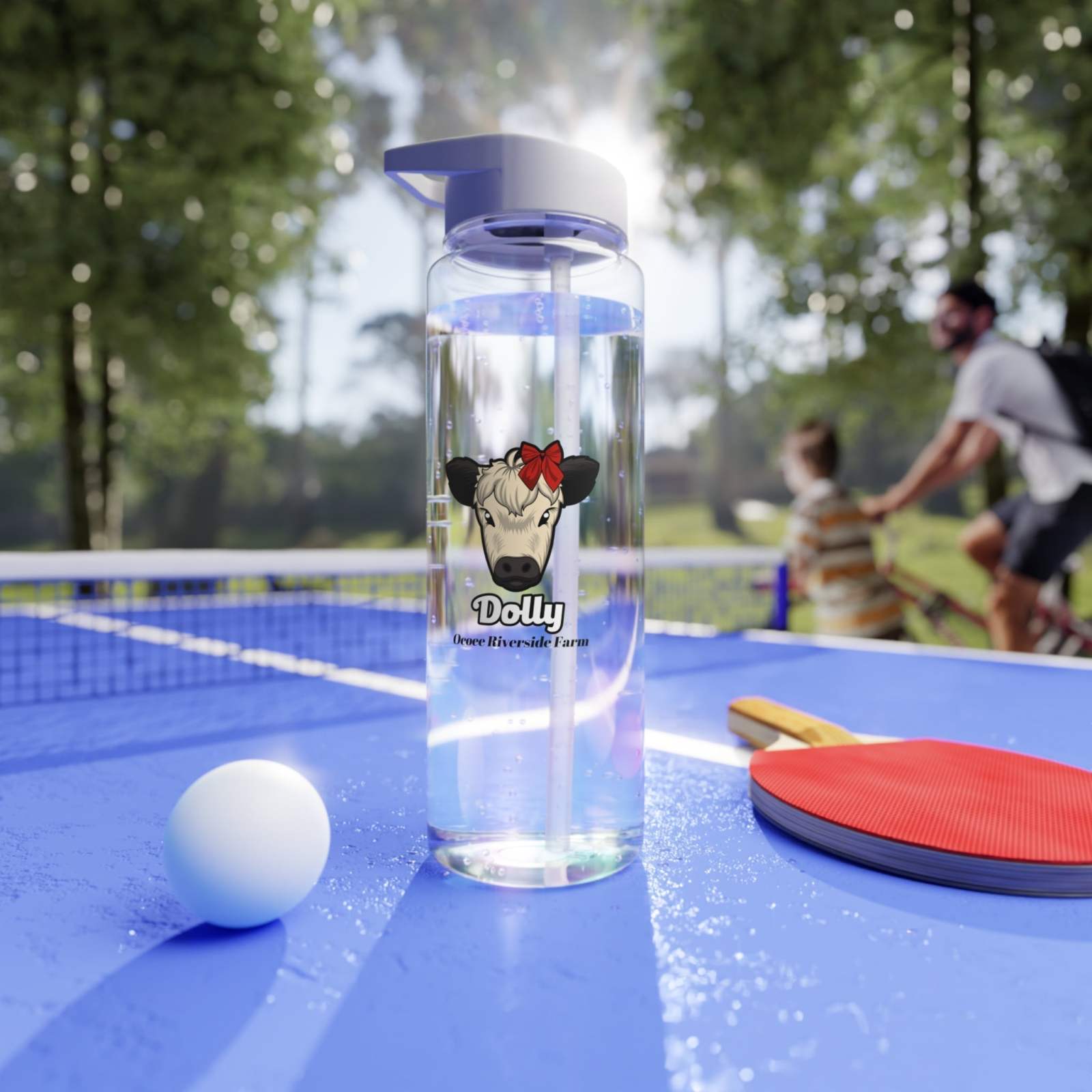 Clear cow print water bottle with straw and purple lid on outdoor table with ping pong paddle and ball, perfect for daily hydration