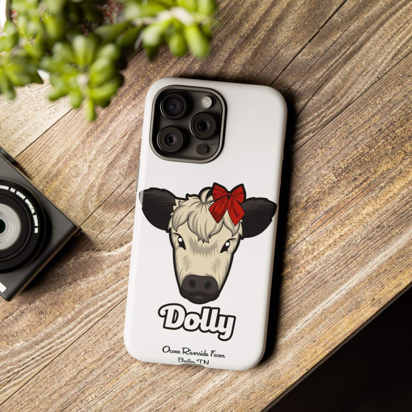 Farmhouse Chic Phone Case with red bow cow design on wooden table.