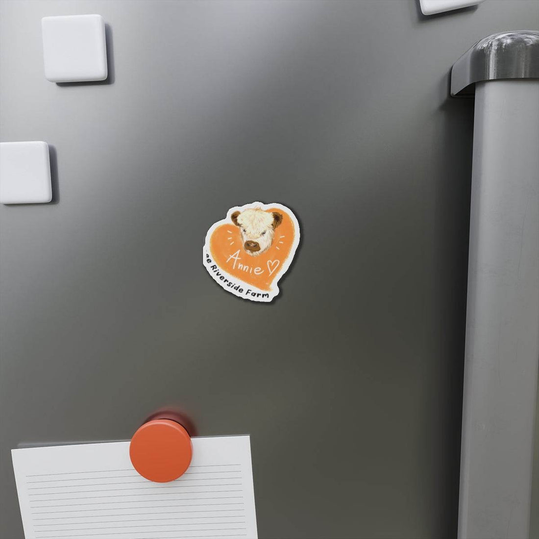 Cute cow design die-cut magnet with an orange heart background on a refrigerator door.
