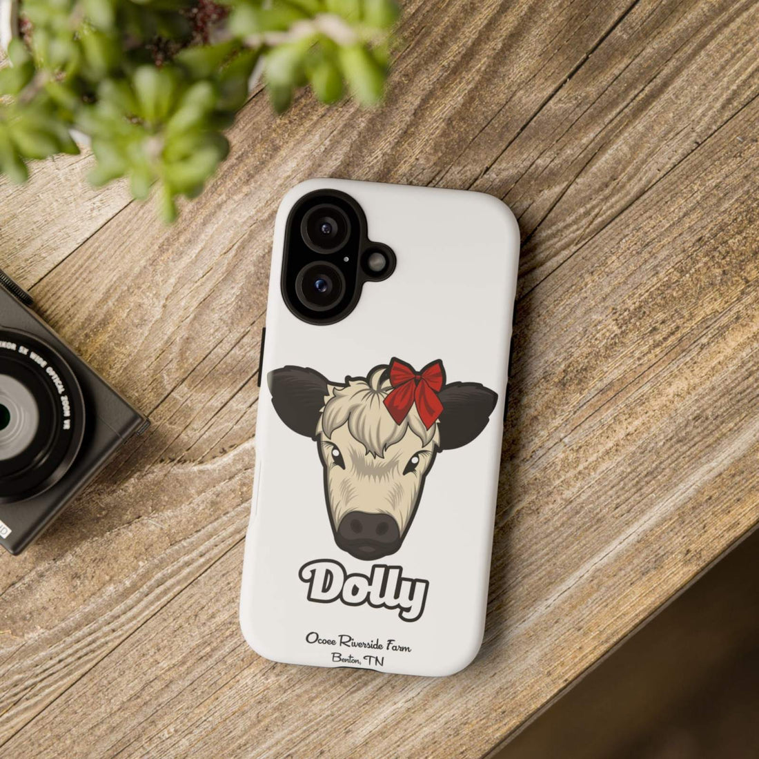 Farmhouse Chic Phone Case with red bow cow design on wooden surface.