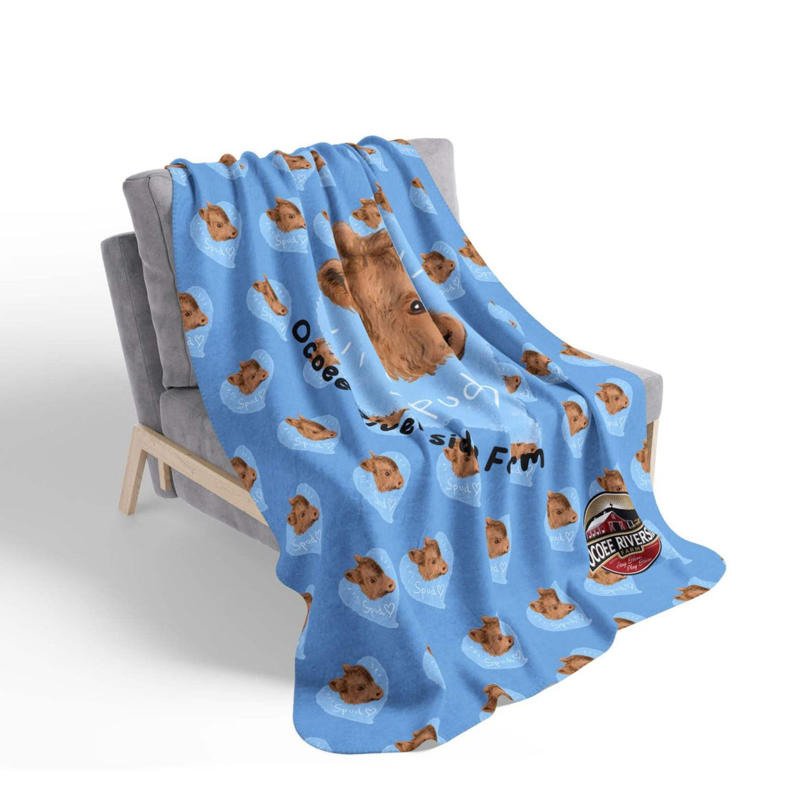 Blue cozy fleece Snuggly Farmhouse Blanket featuring cartoon cow faces and farmhouse design draped over gray chair