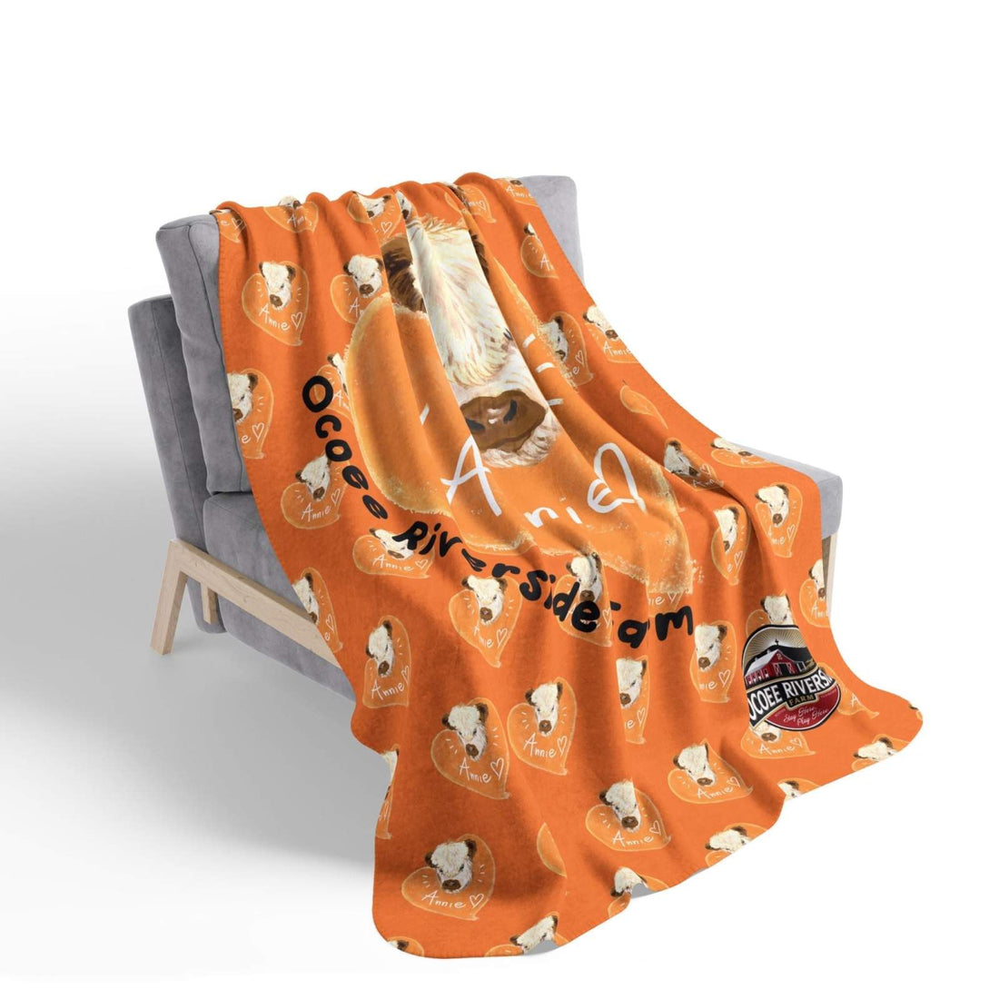 Orange cow-themed Sherpa blanket with cute cow faces and rustic farmhouse design draped over a gray chair