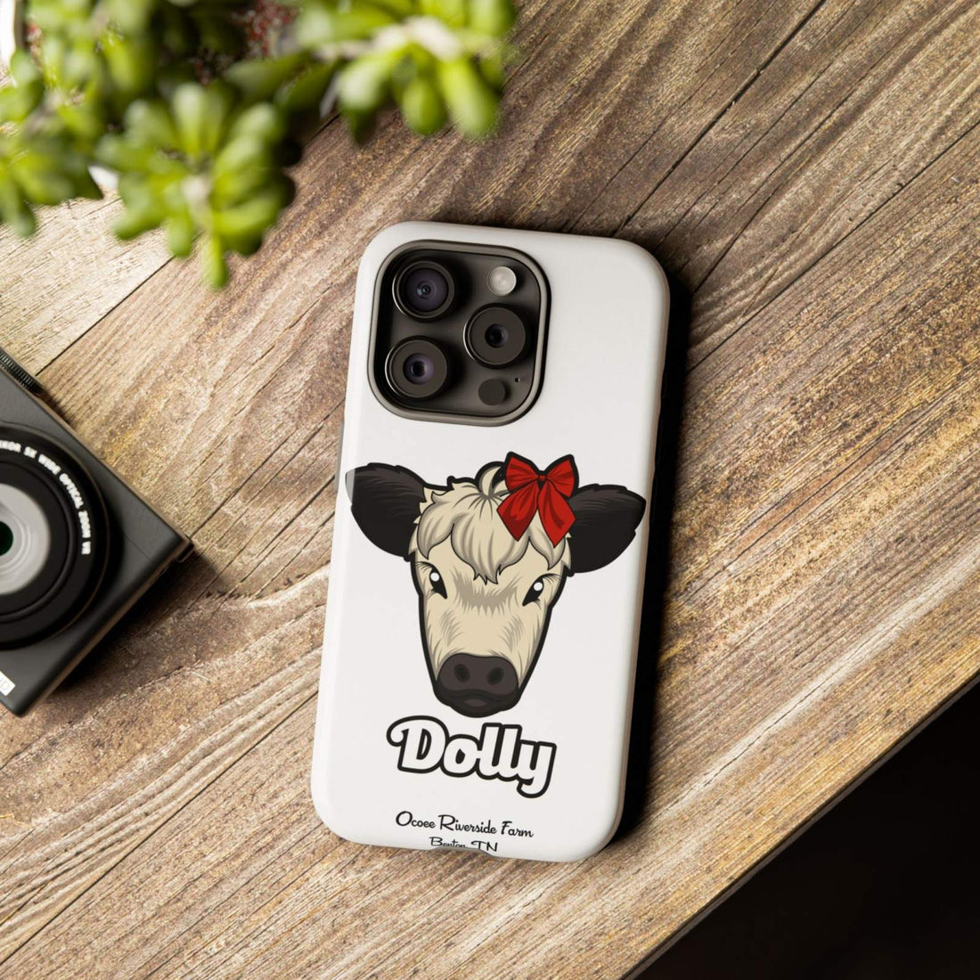Farmhouse Chic Phone Case with Dolly the Cow and Red Bow Design on Rustic Wood Background.