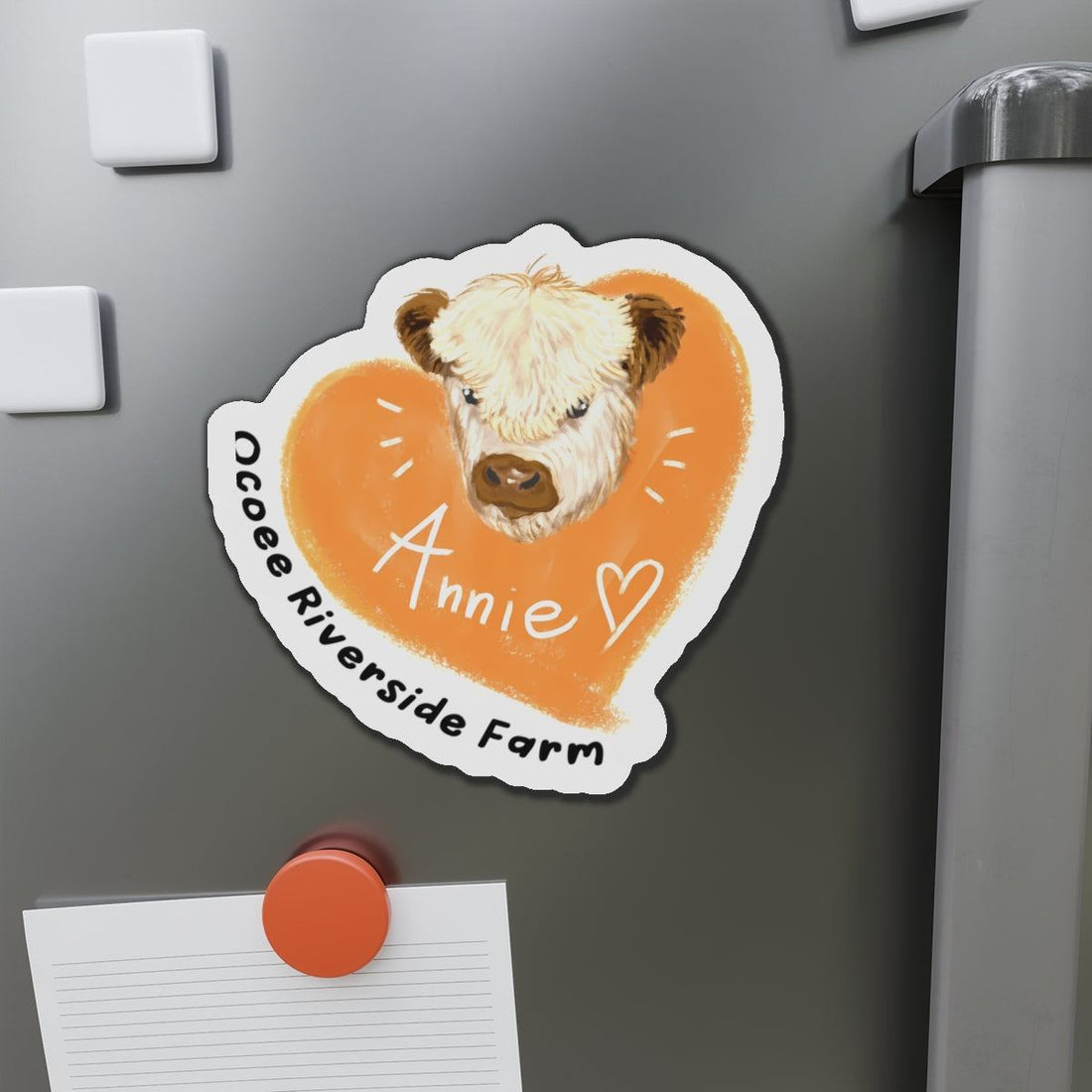 Cute cow design die-cut magnet with a heart background and personalized name on a refrigerator door
