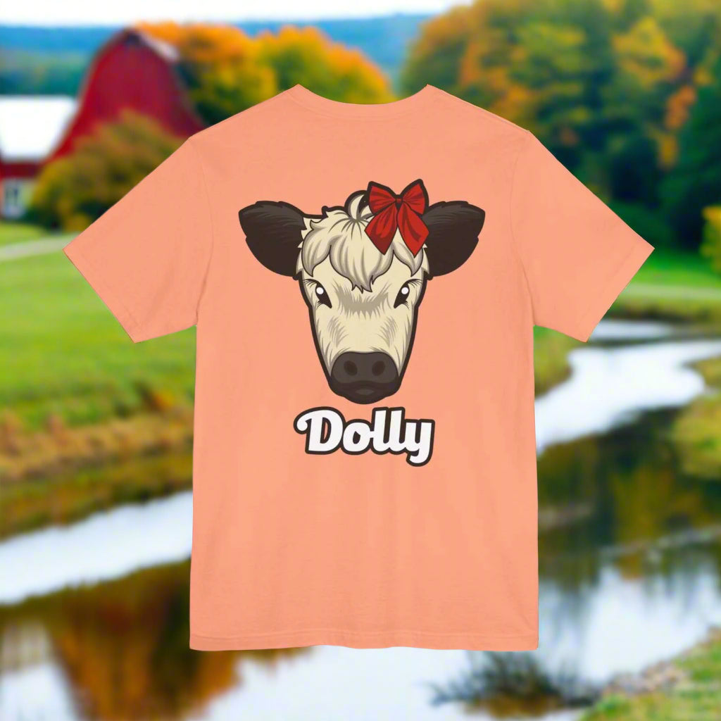 Peach Country Cow Graphic Tee featuring a cow face named Dolly with a red bow