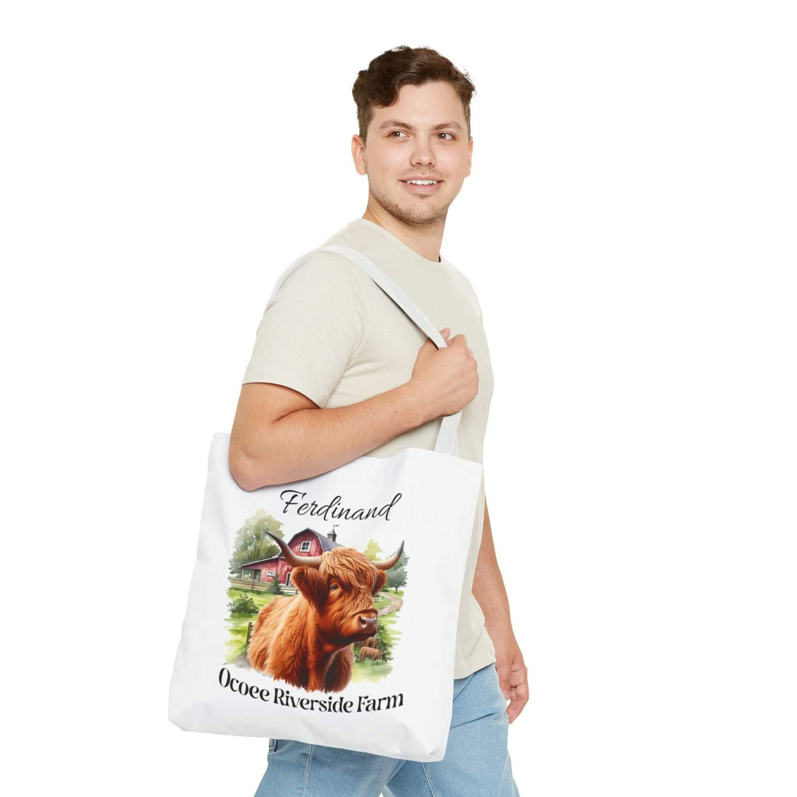 Man carrying white eco-friendly tote bag featuring Ferdinand Scottish Highland cow and Ocoee Riverside Farm design
