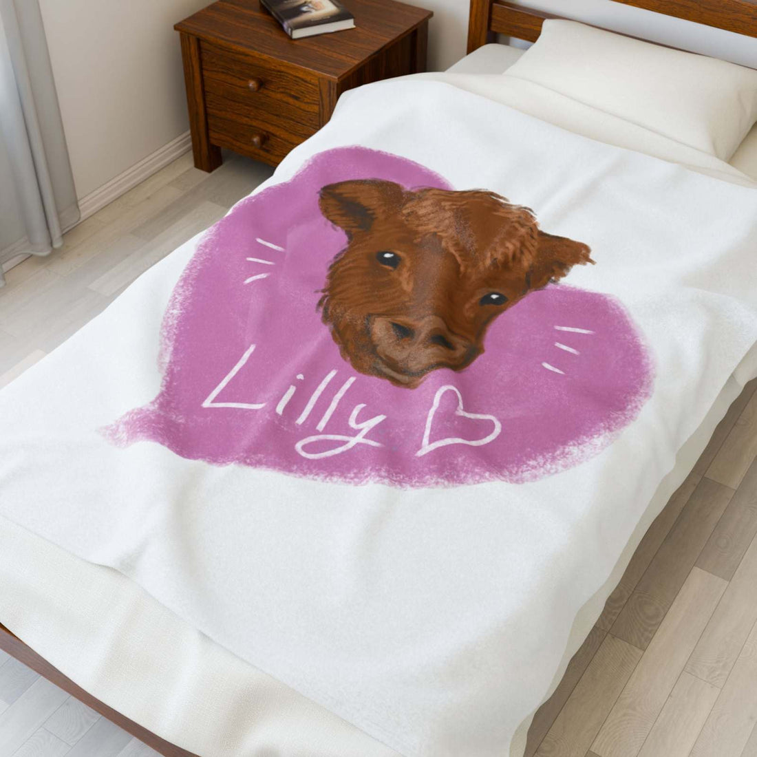 White Cute Cow Plush Blanket with brown cow face design inside a pink heart and the name Lilly written below, displayed on a bed with wooden furniture.