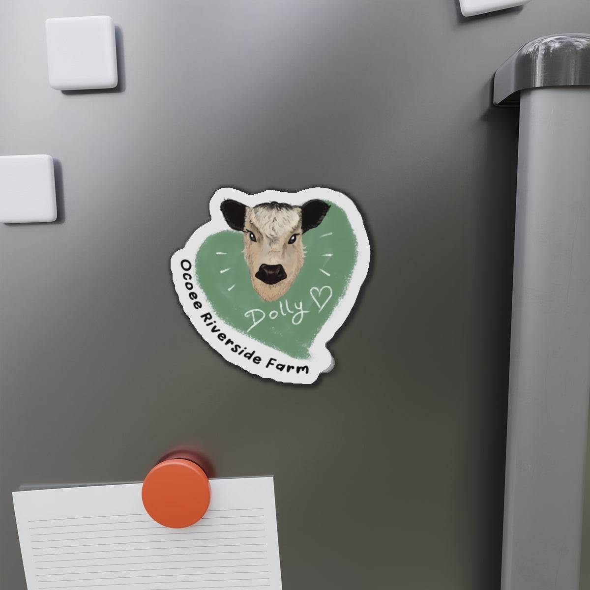 Cute Cow Die-Cut Magnet with cow face illustration and "OCoe Riverside Farm Dolly" text on gray metal surface