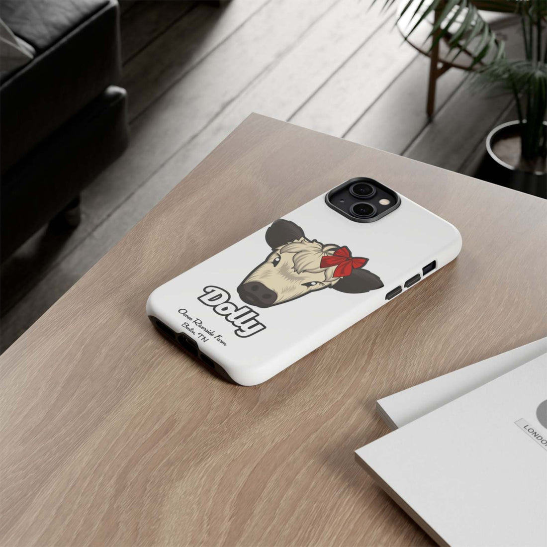 Farmhouse Chic Phone Case with Red Bow Cow Design on Table.