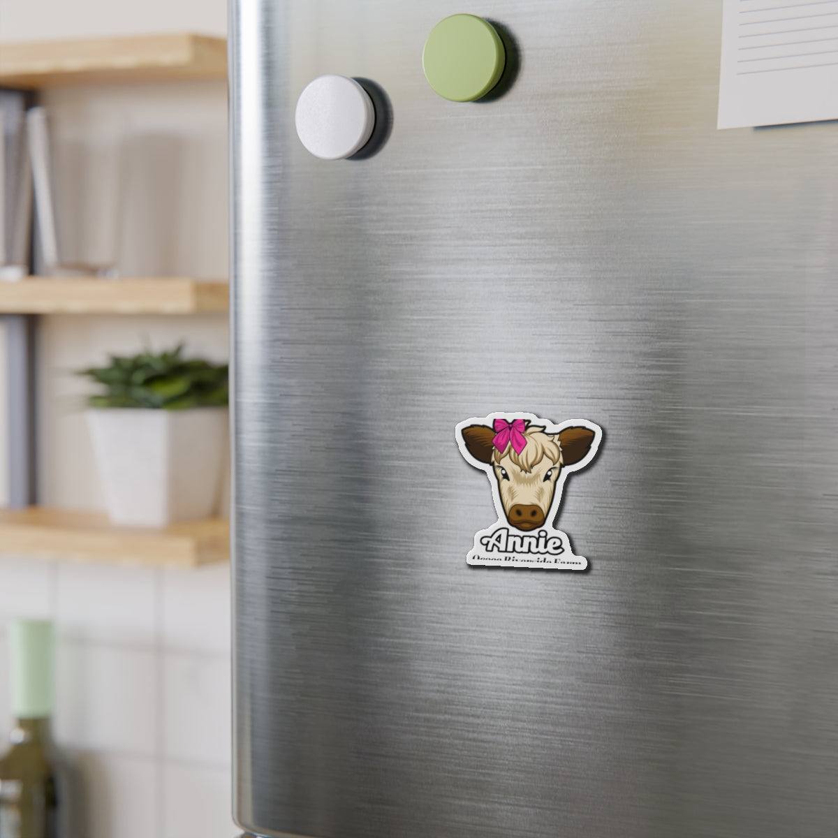 Cow die-cut magnet with cute cow face and pink bow on stainless steel refrigerator door holding papers and notes