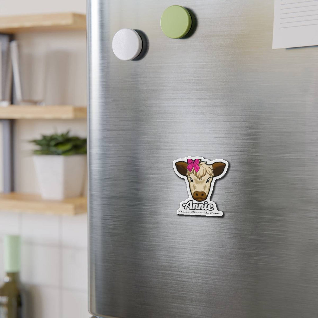 Cow die-cut magnet with cute cow face and pink bow on stainless steel refrigerator door holding papers and notes