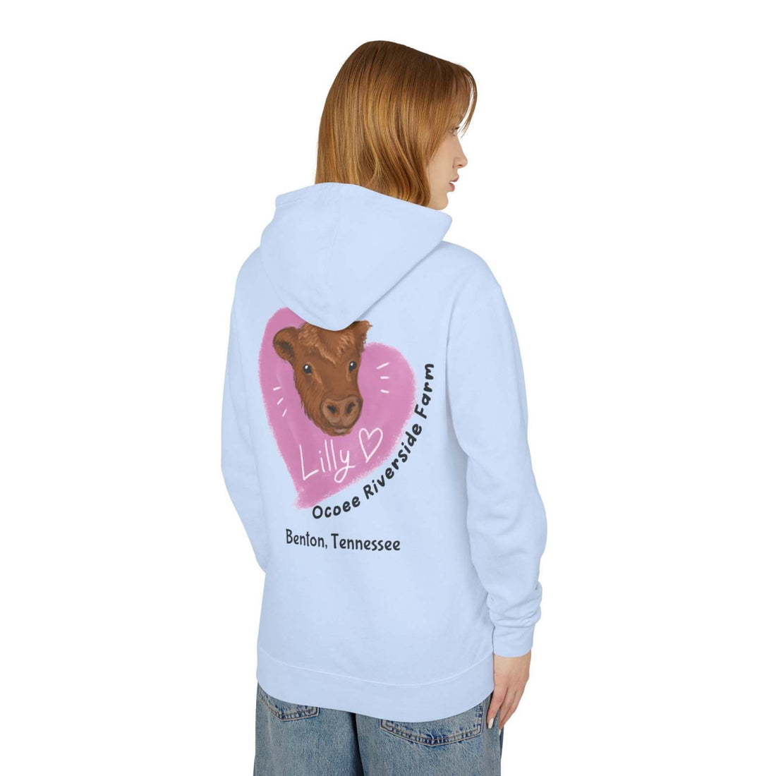 Light blue Cute Cow Hoodie with farm-themed cow graphic and heart design on back, worn by a woman, unisex lightweight sweatshirt from Ocoee Riverside Farm.