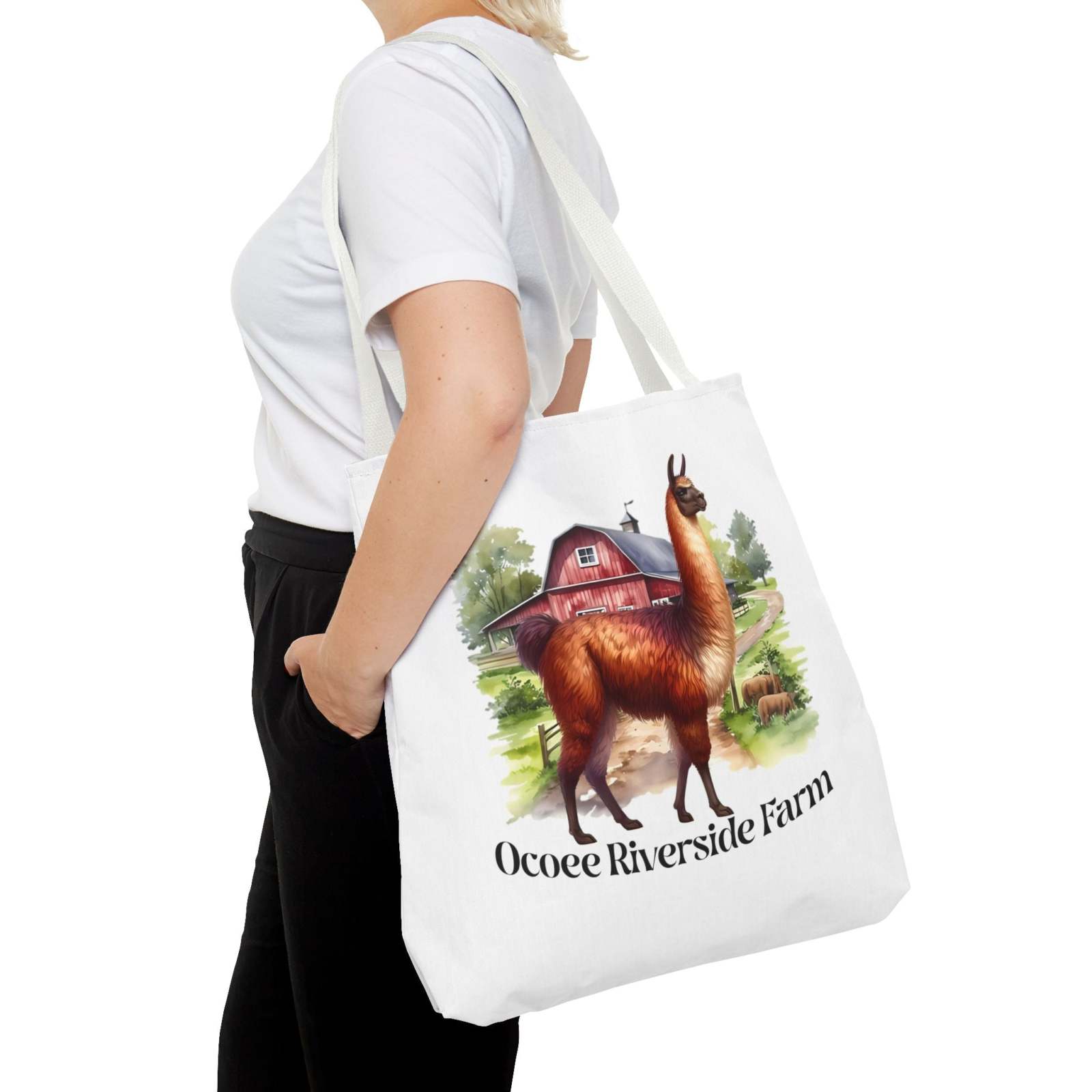 Woman carrying white Eco-Friendly Alpaca Tote Bag with Ocoee Riverside Farm design featuring an alpaca and red barn illustration
