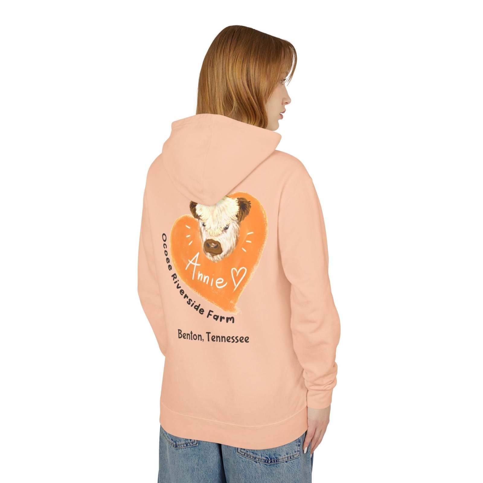 Unisex hooded sweatshirt in peach with adorable cow design and "Annie" text from Ocoee Riverside Farm, Benton Tennessee, worn by a model from the back