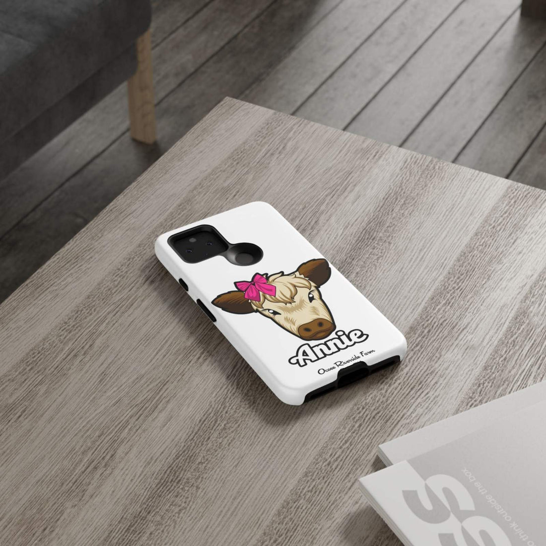 Cute cow phone case with red bow on wooden table; perfect farm animal lover gift.