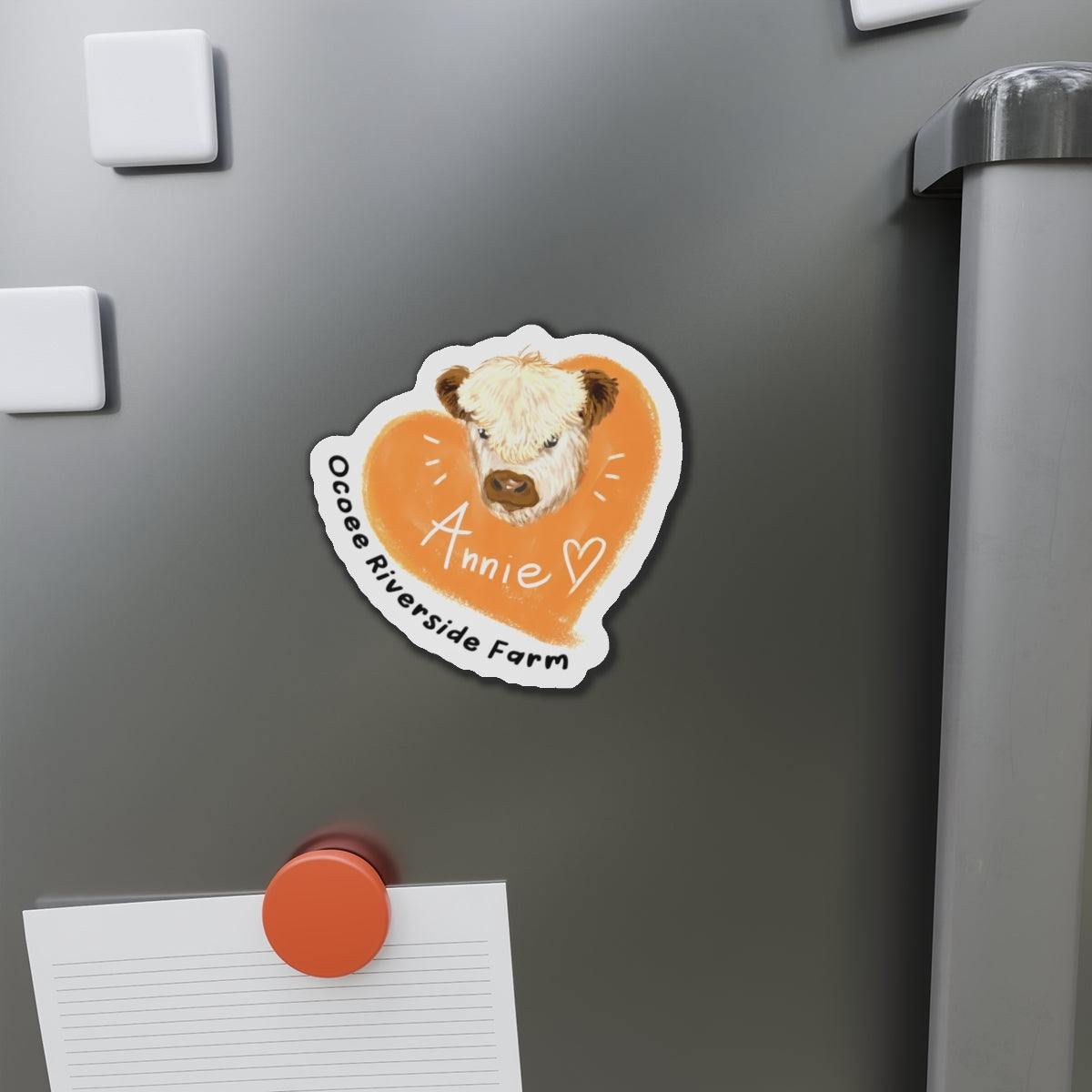 Cute Cow Design die-cut magnet with cow illustration and "Annie" text on a fridge.