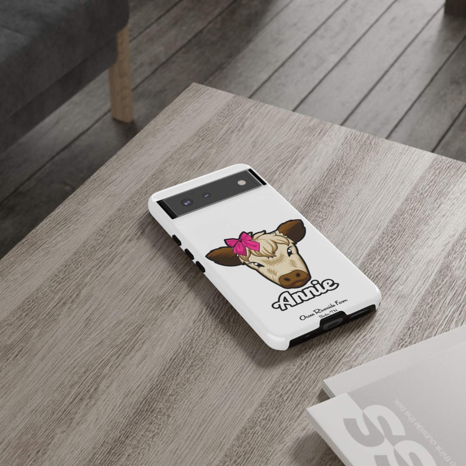 Cow phone case with red bow on table, perfect farm animal lover gift.