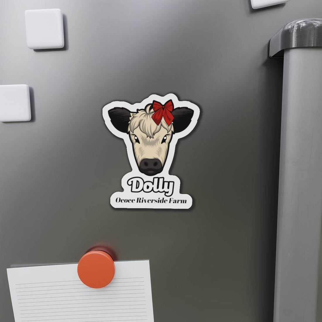 Charming cow die-cut magnet with red bow on cow's head, used as fridge decor and note holder.