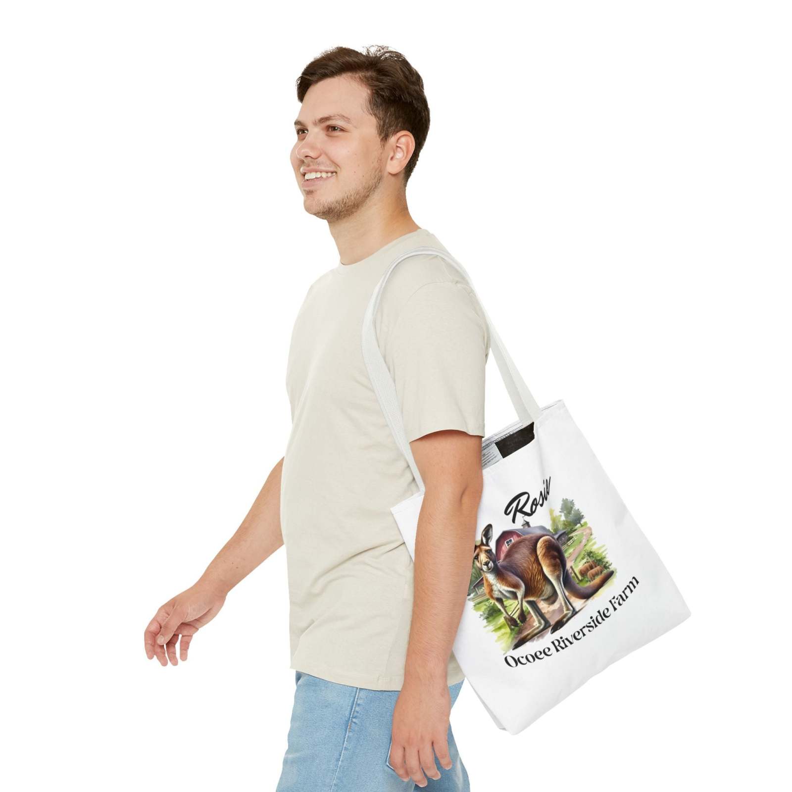 Man wearing beige shirt and jeans carrying a white Rosie Kangaroo Tote Bag with Ocoee Riverside Farm design, eco-friendly shopping bag with kangaroo and farm artwork.