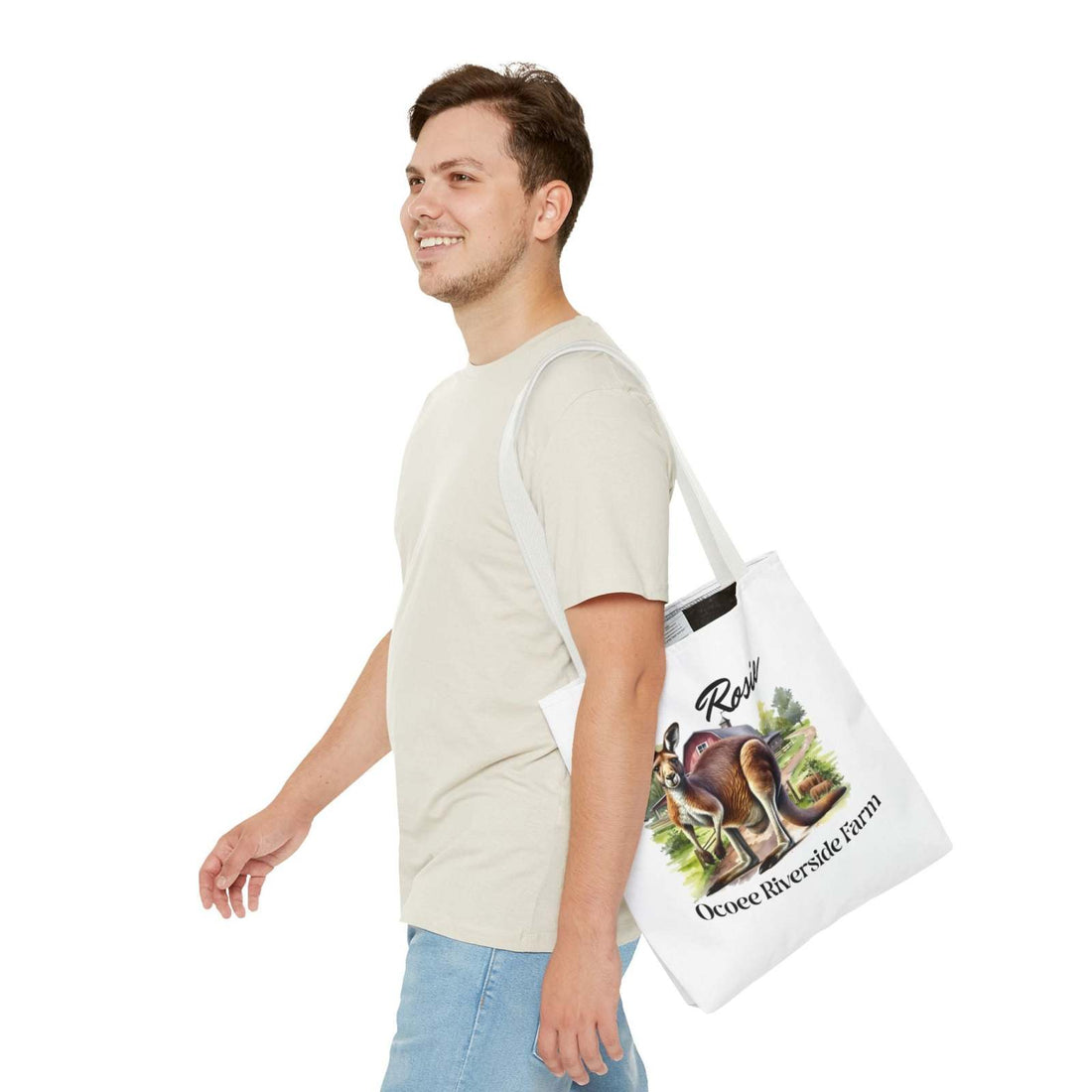 Man wearing beige shirt and jeans carrying a white Rosie Kangaroo Tote Bag with Ocoee Riverside Farm design, eco-friendly shopping bag with kangaroo and farm artwork.
