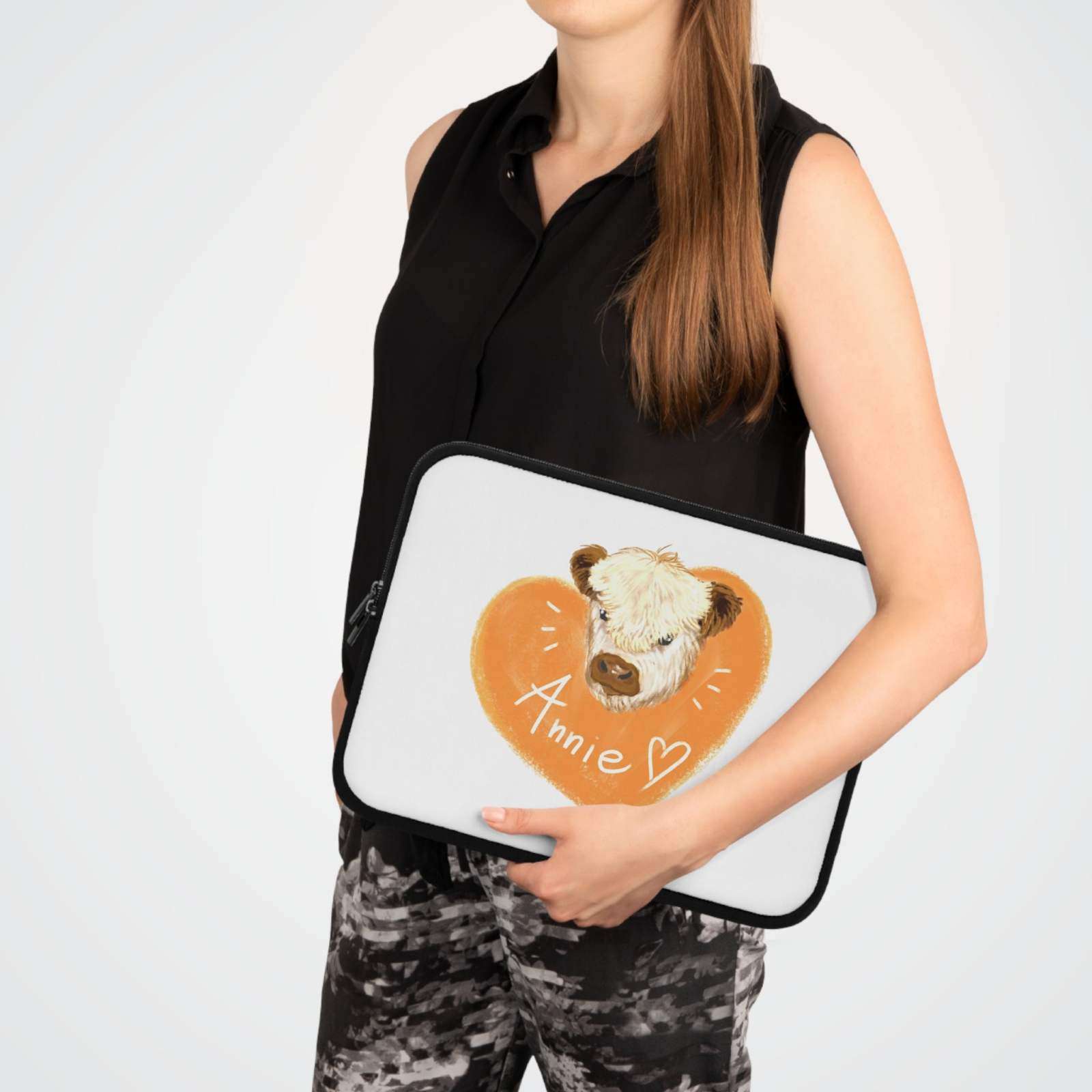 Woman holding a custom cow laptop sleeve with heart design and personalized name Annie