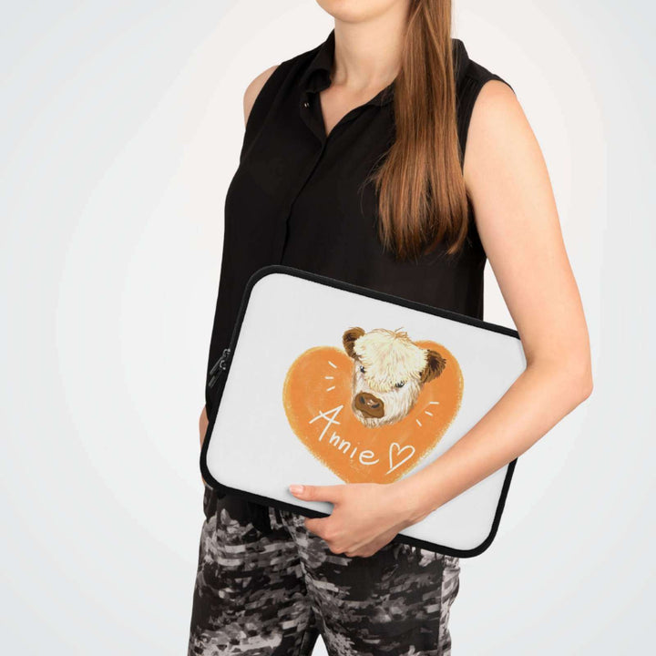 Woman holding a custom cow laptop sleeve with heart design and personalized name Annie