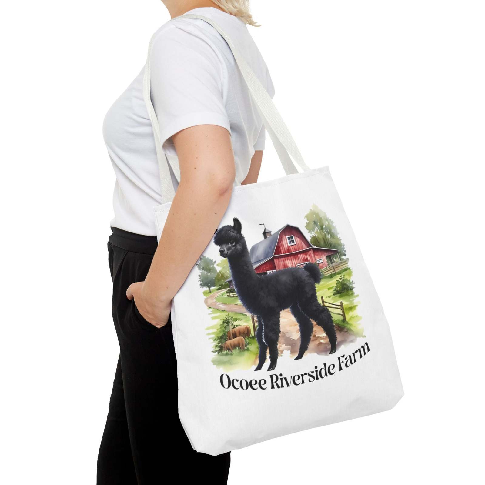 Woman carrying white eco-friendly tote bag with black llama and red barn illustration, labeled Ocoee Riverside Farm