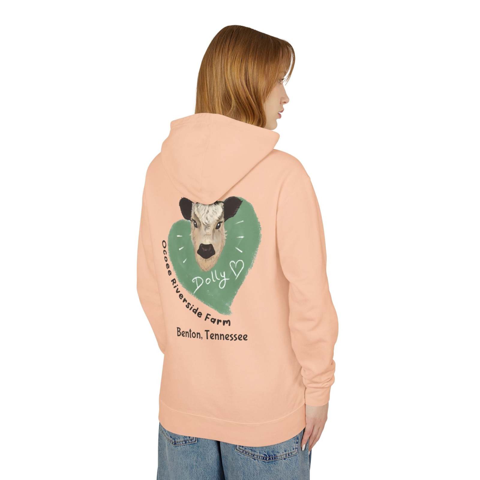 Woman wearing peach Cozy Cow Hoodie with cow graphic and "Dolly" text on back